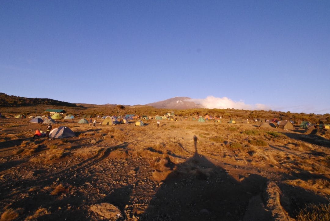 The red glow of the setting sun over camp as the cloud melts away from Kibo peak